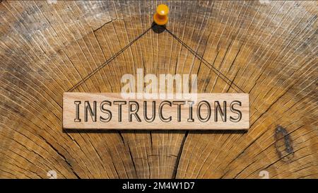 Das Wort Anweisungen. Hintergrundlogbuch auf Holzplatte geschrieben. Stockfoto