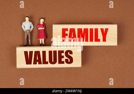 Bildungs- und Menschenkonzept. Auf Holzblöcken mit der Inschrift "Familienwerte" gibt es Miniaturfiguren von Menschen. Stockfoto