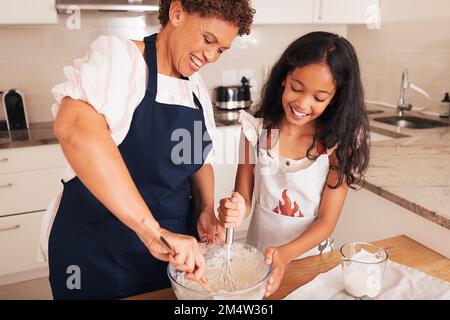 Lächelnde Großmutter und Enkelin mischen Teig in einer Schüssel Stockfoto