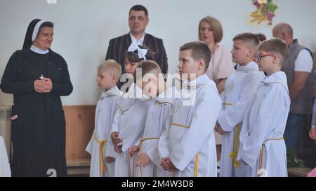 Pervomaysk, Weißrussland - 17. Juni 2022: Kinder in der Kirche bei ihrer ersten katholischen Kommunion. Stockfoto