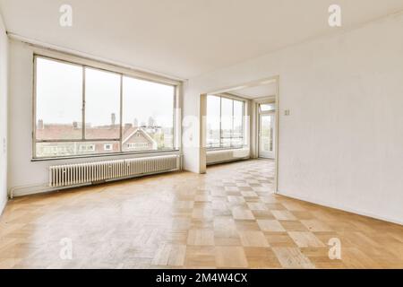 Ein leeres Zimmer mit Holzfußboden und großen Fenstern mit Blick auf die Stadt Stockfoto