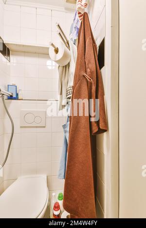 Ein Badezimmer mit einem Handtuch an der Wand neben einer Toilette und einer Rolle Toilettenpapier Stockfoto