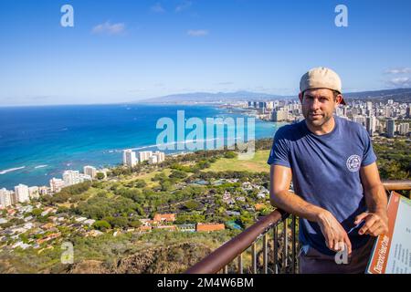 Porträt einer jungen Weißen, die ihren Urlaub auf der Insel O'ahu, Hawaii, mit der Stadt Honolulu im Hintergrund genießt Stockfoto