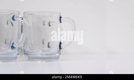 Zwei leere transparente Teegläser stehen nebeneinander auf einem hellen Hintergrund. Konzentrieren Sie sich auf den Griff. Der richtige Platz für Text oder Design Stockfoto