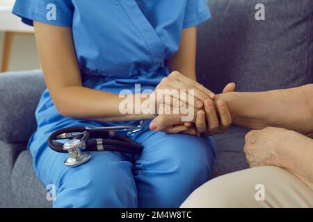 Pflegeperson oder Arzt, die ältere Frauen an den Händen hält Stockfoto