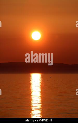 Isle of Arran, Schottland, Großbritannien. Sonnenuntergang über der Insel vom Strand in Ayr. Bekannt als der schlafende Riese aufgrund seines Umrisses, besonders von der Ayrshire Coast aus gesehen. Sonnenuntergang im Firrth von Clyde. Stockfoto