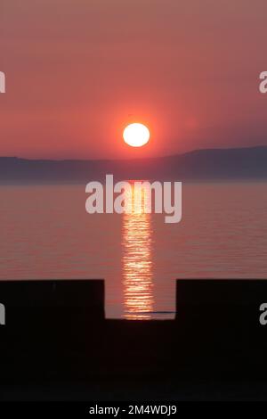 Isle of Arran, Schottland, Großbritannien. Sonnenuntergang über der Insel vom Strand in Ayr. Bekannt als der schlafende Riese aufgrund seines Umrisses, besonders von der Ayrshire Coast aus gesehen. Sonnenuntergang im Firrth von Clyde. Stockfoto