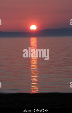 Isle of Arran, Schottland, Großbritannien. Sonnenuntergang über der Insel vom Strand in Ayr. Bekannt als der schlafende Riese aufgrund seines Umrisses, besonders von der Ayrshire Coast aus gesehen. Sonnenuntergang im Firrth von Clyde. Stockfoto