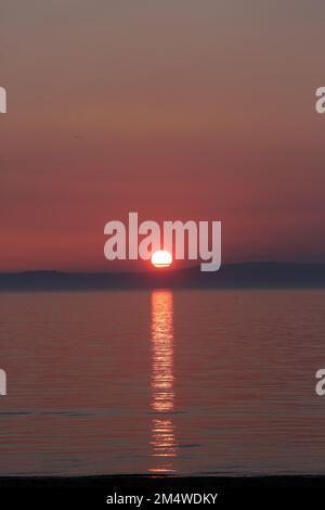 Isle of Arran, Schottland, Großbritannien. Sonnenuntergang über der Insel vom Strand in Ayr. Bekannt als der schlafende Riese aufgrund seines Umrisses, besonders von der Ayrshire Coast aus gesehen. Sonnenuntergang im Firrth von Clyde. Stockfoto