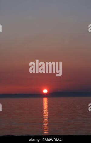 Isle of Arran, Schottland, Großbritannien. Sonnenuntergang über der Insel vom Strand in Ayr. Bekannt als der schlafende Riese aufgrund seines Umrisses, besonders von der Ayrshire Coast aus gesehen. Sonnenuntergang im Firrth von Clyde. Stockfoto