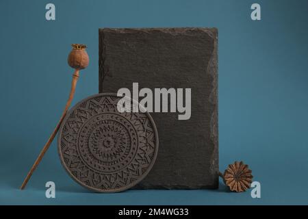 Abstrakte Naturszene aus Steinen, getrockneter Mohnsamen. Dunkelblauer Hintergrund für kosmetische Männer. Minimalistische Stillleben-Komposition Stockfoto
