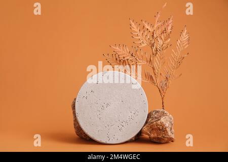 Abstrakte Darstellung der Naturszene Herbstvorstellung aus Naturstein, Herbstlaub, Podium-Präsentationskosmetik auf beigem Hintergrund. Stockfoto
