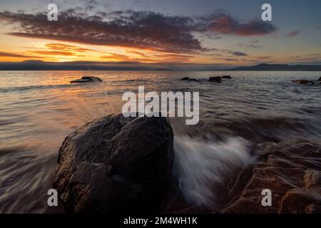 Ruhiger Morgen am Lake Superior, wenn die Sonne aufgeht und den Horizont bricht, um einen neuen Tag in der Nähe von Marquette Michigan auf der oberen Halbinsel zu erleuchten. USA Stockfoto