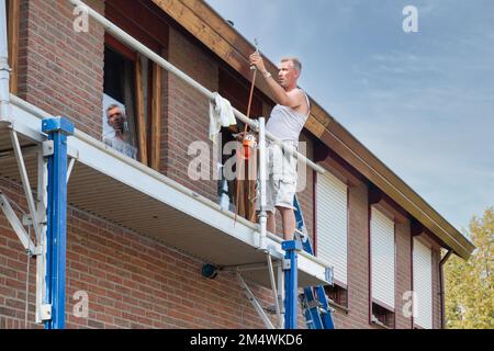 Urk, Niederlande - 28. August 2019: Maler beschäftigt sich mit dem Entfernen alter Farbe und der Vorbereitung eines Fensterrahmens für die Neuanstrich Stockfoto