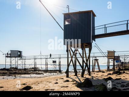 Fischerhütten mit einem großen quadratischen Aufzugsnetz namens „carrelet“ stehen am Strand in Saint-Nazaire, Frankreich, bei Ebbe an einem sonnigen Sommertag. Stockfoto