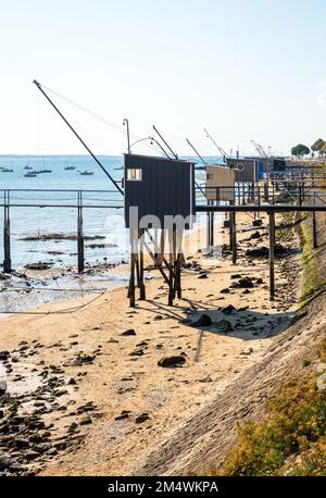 Fischerhütten mit einem großen quadratischen Aufzugsnetz namens „carrelet“ stehen am Strand in Saint-Nazaire, Frankreich, bei Ebbe an einem sonnigen Sommertag. Stockfoto