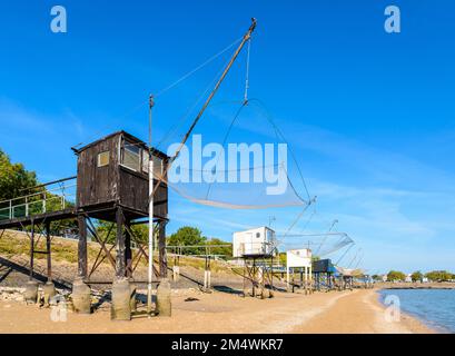 Fischerhütten mit einem großen quadratischen Aufzugsnetz namens „carrelet“ stehen am Strand in Saint-Nazaire, Frankreich, bei Ebbe an einem sonnigen Sommertag. Stockfoto
