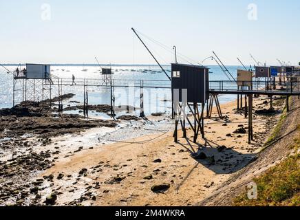 Fischerhütten mit einem großen quadratischen Aufzugsnetz namens „carrelet“ stehen am Strand in Saint-Nazaire, Frankreich, bei Ebbe an einem sonnigen Sommertag. Stockfoto