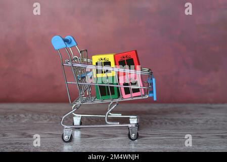 Einkaufswagen und bunte Bausteine mit Geschenkbox-Symbol. Einkaufen, Geschenk kaufen, Black friday Sale Konzept Stockfoto