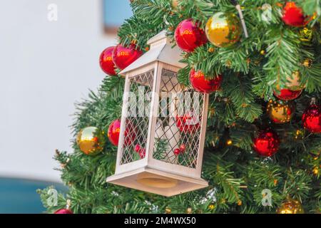 Laterne und Kerzen als Weihnachtsdekoration auf den Zweigen einer Fichte, rote Kugeln, Zapfen und Beeren, Weihnachtshintergrund Stockfoto