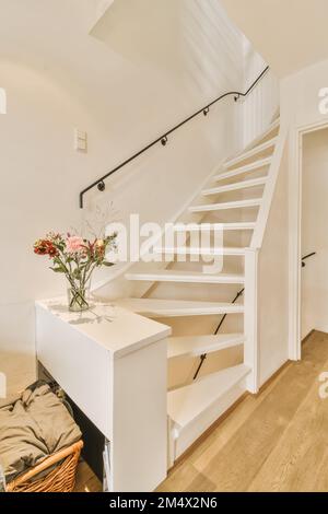 Ein Wohnzimmer mit ein paar Blumen in der Vase auf dem Tisch und Treppen, die zum zweiten Stock führen Stockfoto