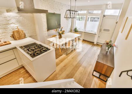 Küche und Essbereich in einem kleinen Apartment mit weißen Wänden, Holzboden und einem Ofen auf dem Herd Stockfoto