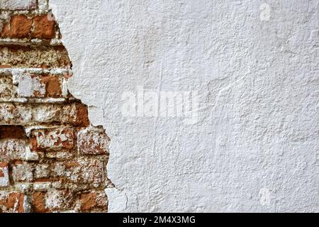 Textur alter Ziegelmauern mit zusammengefallenem Putz. Hintergrund einer schäbigen Gebäudefläche. Zerstörte Beton- und Ziegelwand mit heruntergefallenem Putz. Weathe Stockfoto