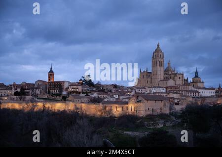 Segovia, Spanien - 4. Januar 2022: Panoramablick auf Segovia mit den Türmen der Kathedrale und dem dramatischen Himmel in der Dämmerung Stockfoto