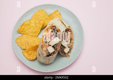 Mexikanischer Rindfleischburrito auf einem kleinen Teller mit Chips Nachos auf dem Teller Stockfoto