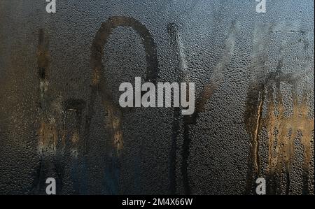 Das Wort Liebe steht auf nassem Glas geschrieben. Die Inschrift tropft runter. Stockfoto