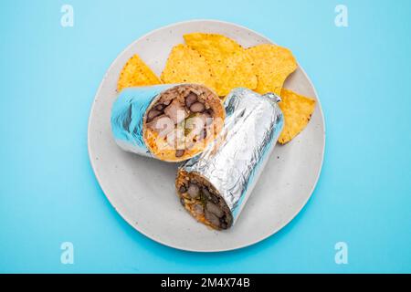 Mexikanischer Rindfleischburrito auf einem kleinen Teller mit Chips Nachos auf dem Teller Stockfoto
