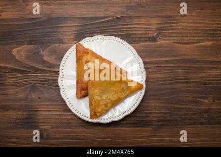 Zwei Samosas mit Fleisch und Gemüse auf einem kleinen weißen Teller Stockfoto