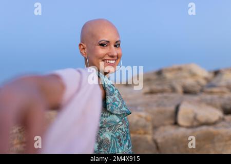 Glückliche Frau mit Alopezie, die den Sonnenuntergang genießt Stockfoto