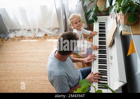 Ein Mann, der seiner Tochter zu Hause Klavier beibringt Stockfoto