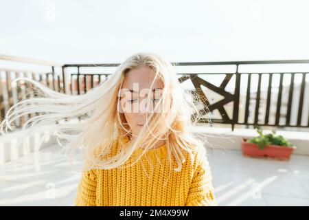 Blonde Frau mit windgepeitschtem Haar auf der Terrasse Stockfoto