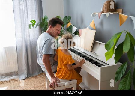 Vater unterrichtet Tochter Klavier zu Hause Stockfoto