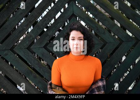 Junge Frau, die vor einer Holzwand steht Stockfoto