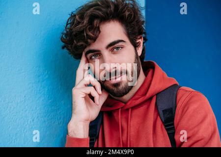 Junger Mann mit Bart an der blauen Wand Stockfoto