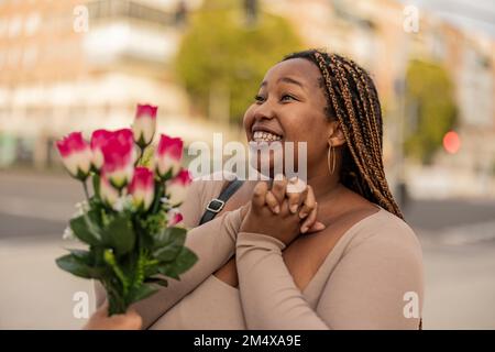 Glückliche junge Frau mit einem Mann, der einen Blumenstrauß gibt Stockfoto