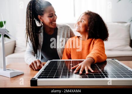 Glückliche Mutter und Tochter mit Solarzellen zu Hause Stockfoto