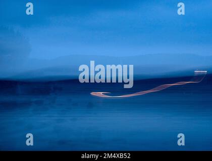 Deutschland, Baden-Württemberg, Radolfzell, Lichtpfade über dem Bodensee in der blauen Abenddämmerung Stockfoto