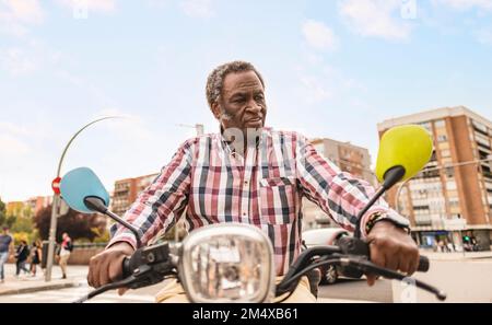 Älterer Mann, der Roller in der Stadt fährt Stockfoto