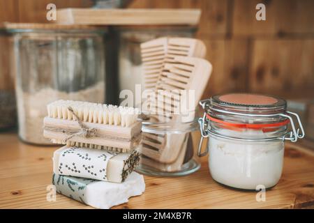 Ein Stapel Seifenleisten und eine Scheuerbürste mit Kammaufsätzen und einem Becher auf dem Tisch Stockfoto