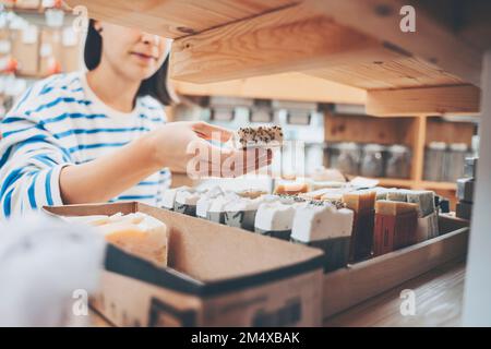 Eine Frau, die ein duftendes Seifenbarren in einem Abfalllager hält Stockfoto