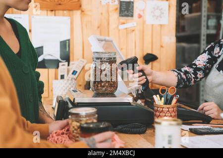 Eine Verkäuferin scannt an der Kasse die Kastendose auf der Waage Stockfoto
