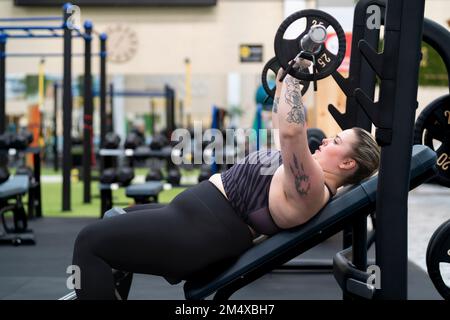 Junge Frau, die im Fitnessstudio Brustübungen macht Stockfoto