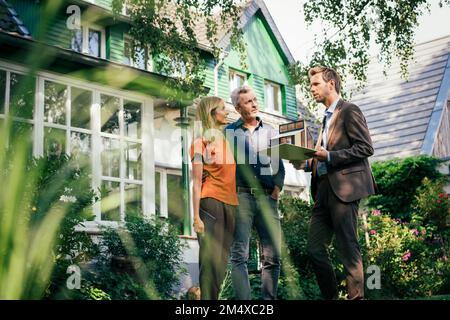 Reifes Paar, das über ein Modellhaus diskutiert, das im Garten steht Stockfoto