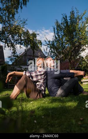 Mann und Frau sitzen mit geschlossenen Augen auf Gras im Garten Stockfoto