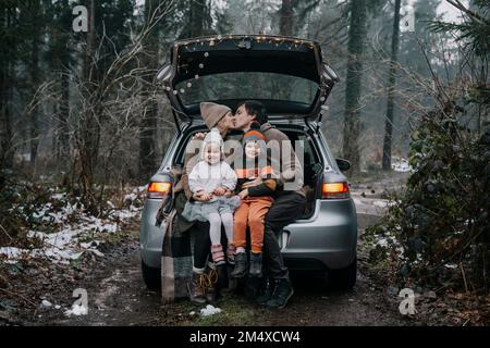 Eltern, die sich im Kofferraum von Kindern auf den Mund küssen Stockfoto