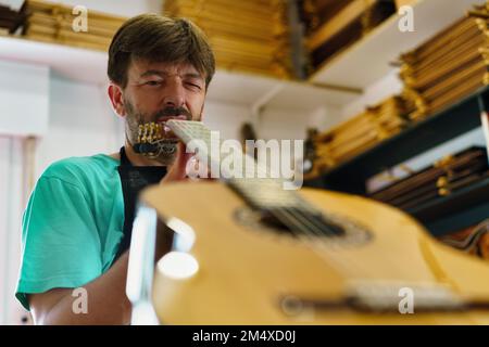 Handwerker, der Gitarre in der Werkstatt studiert Stockfoto